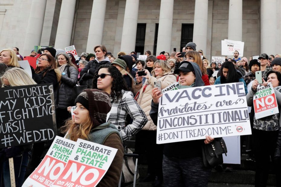 People hold signs at a rally held in opposition to a proposed bill that would remove parents’ ability to claim a philosophical exemption to opt their school-age children out of the combined measles, mumps and rubella vaccine, at the Capitol in Olympia, Wash., Feb. 2019.